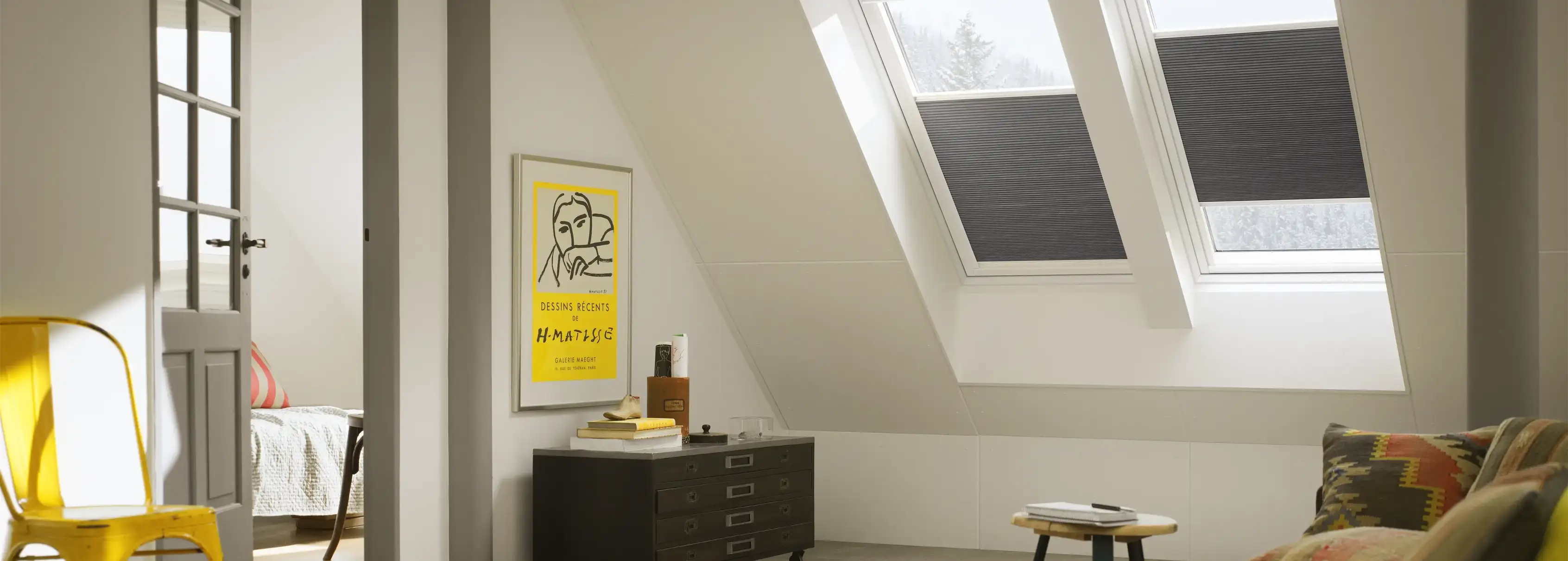 Attic living space with sloped ceiling and VELUX roof windows, cozy decor.