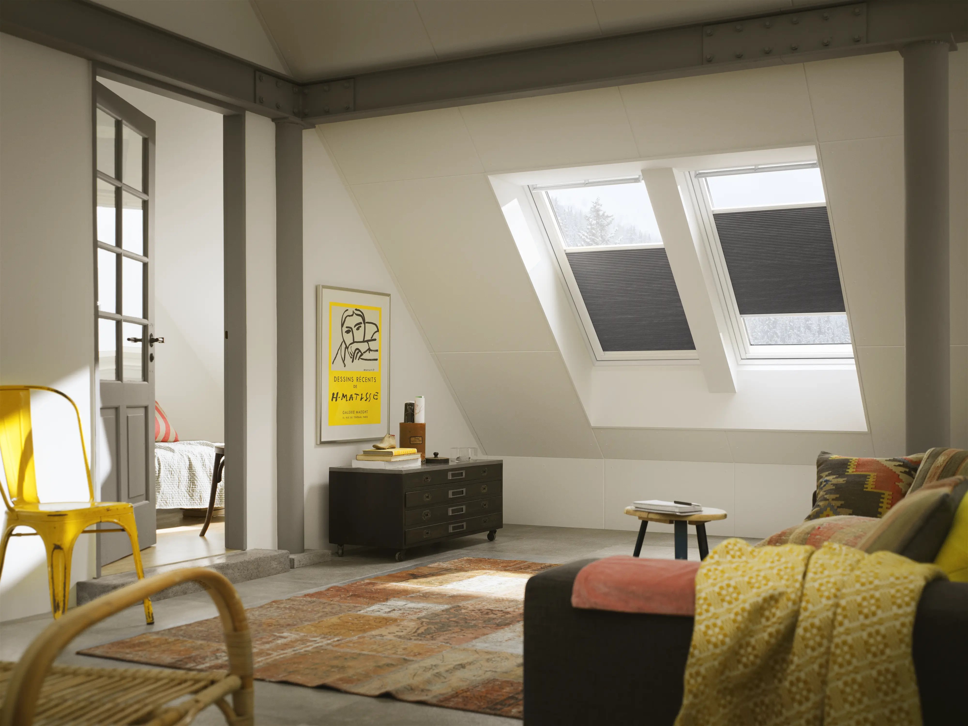 Attic living space with sloped ceiling and VELUX roof windows, cozy decor.