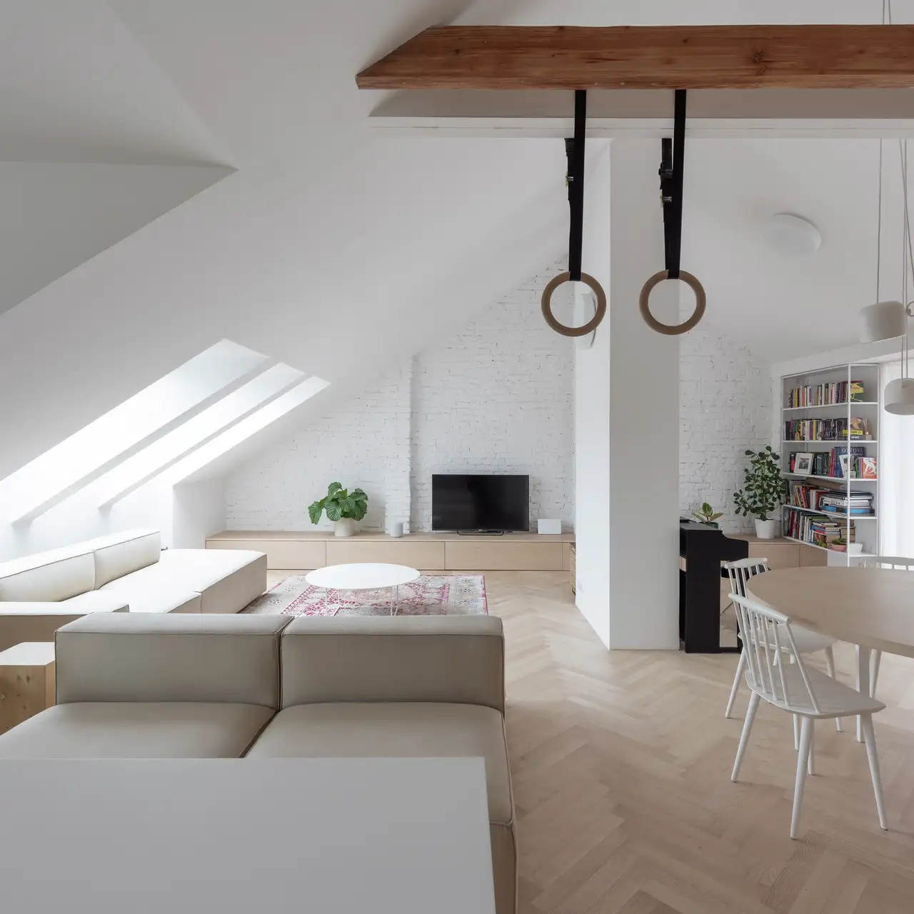 Appartement sous combles avec fenêtres de toit et une fenêtre en façade, murs et mobilier dans des tons clairs
