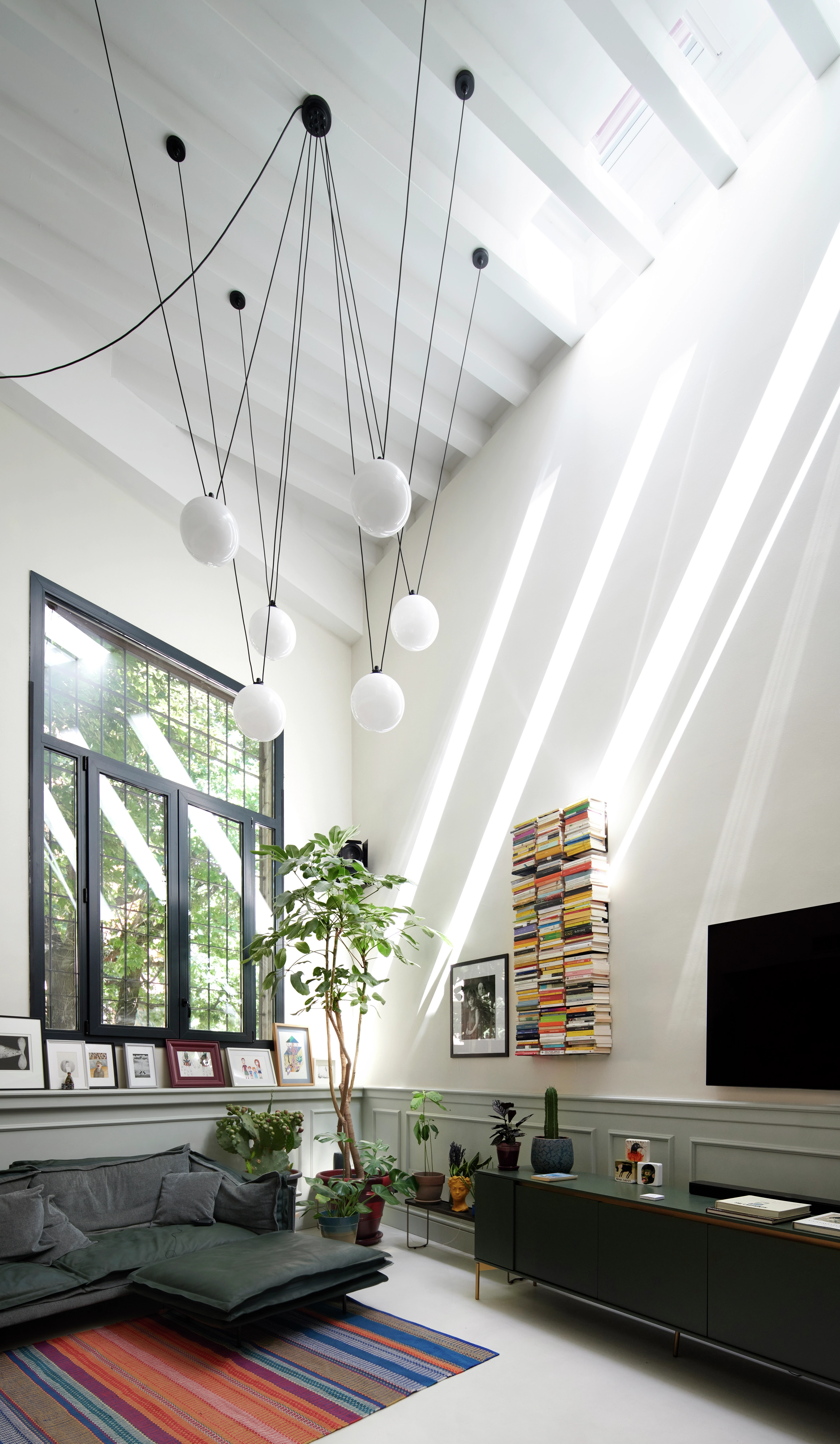Salon lumineux avec des fenêtres de toit VELUX, décoration moderne et lumières sphériques suspendues.