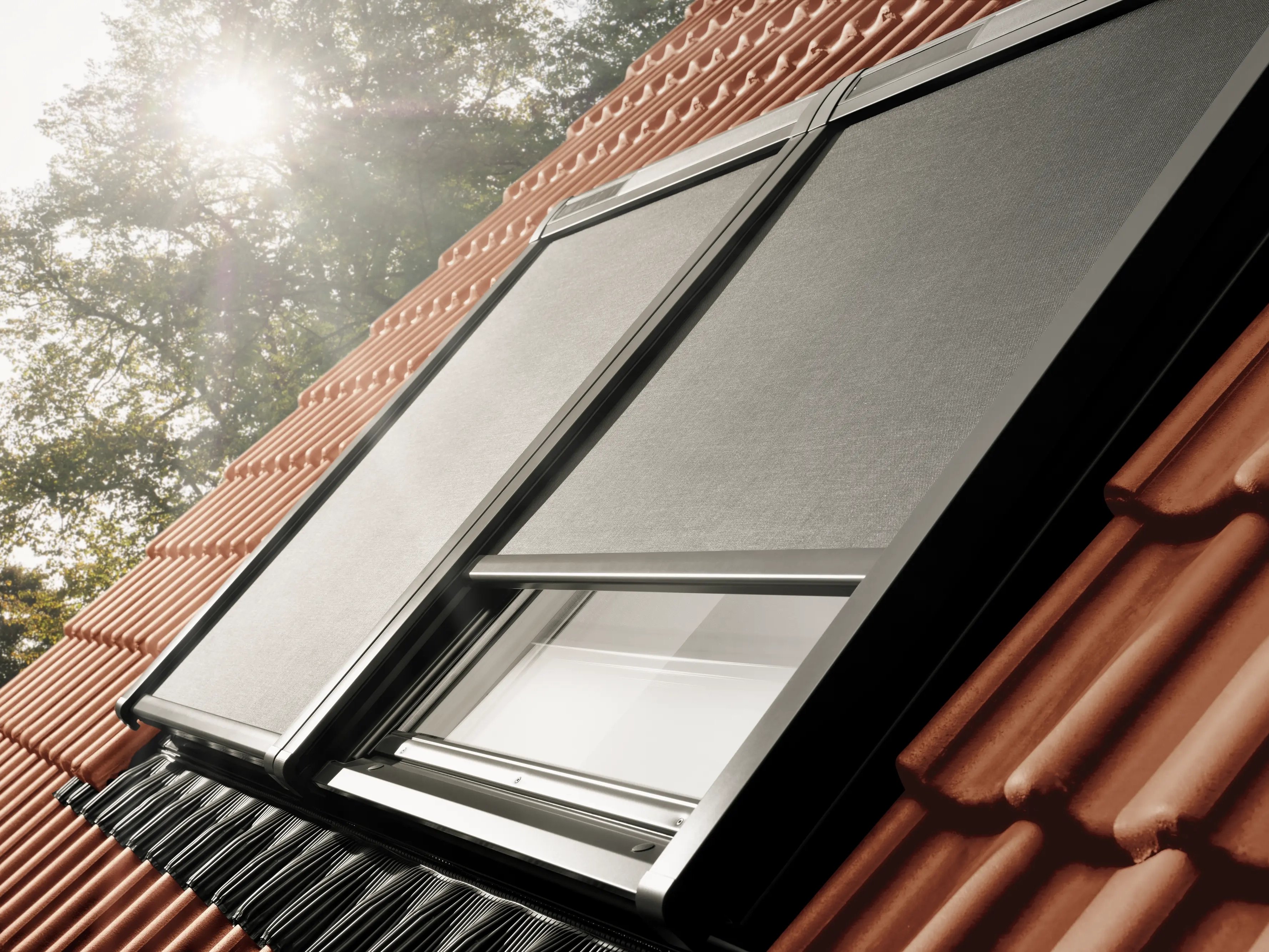 VELUX roof window on a red tiled roof with awning blinds.