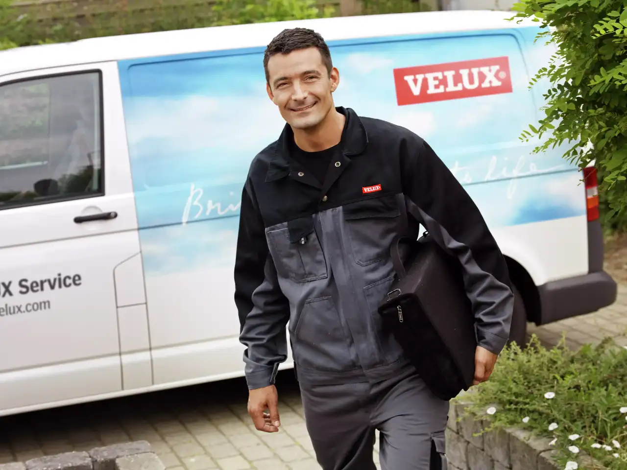 VELUX-Servicetechniker nähert sich einem markierten Firmenfahrzeug für Dachflächenfenster-Dienstleistungen.