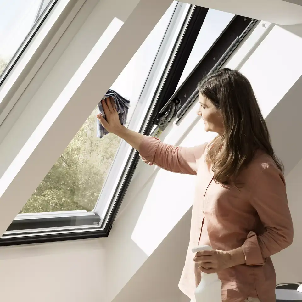 mulher a limpar uma janela de sótão VELUX