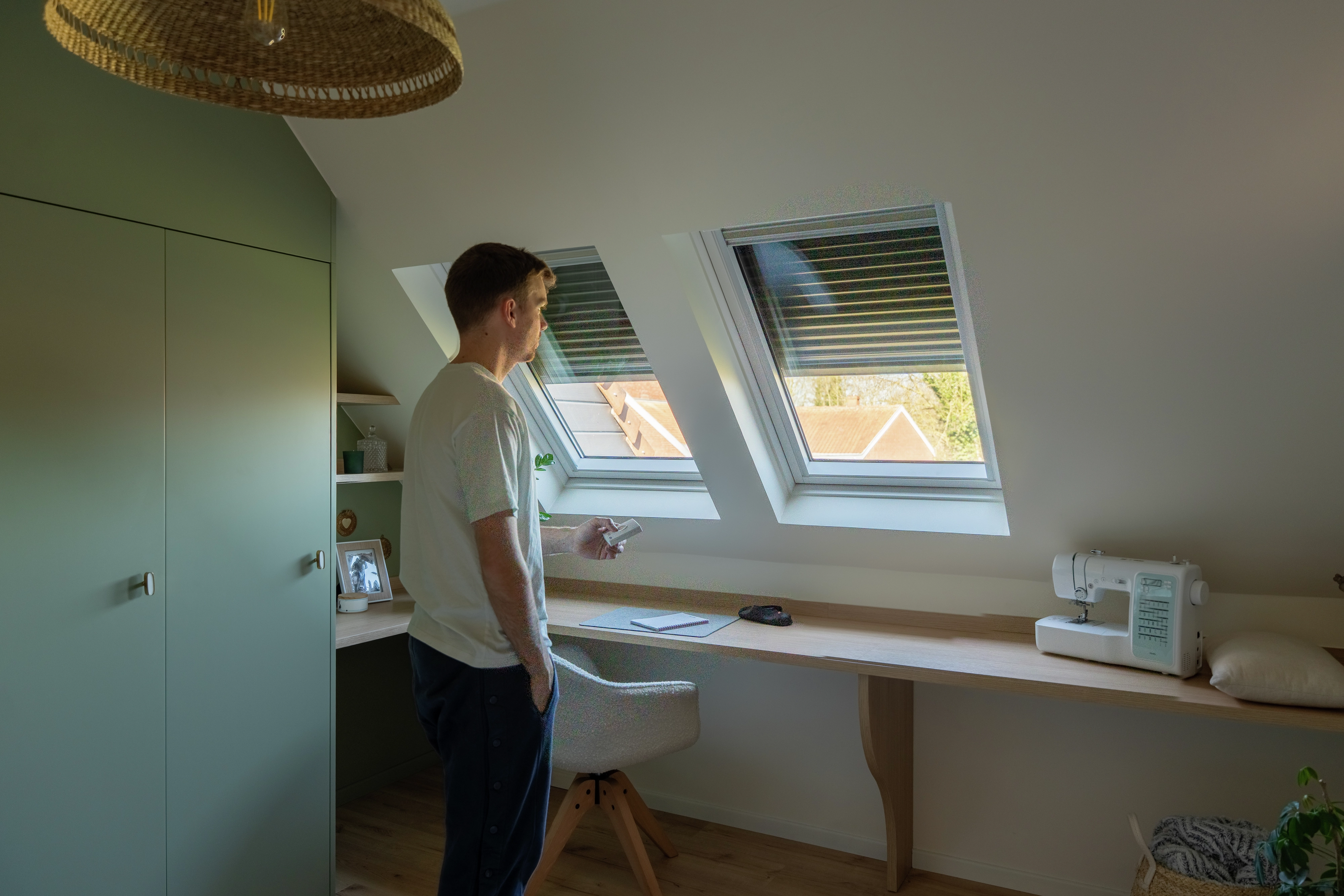 Homme fermant un volet roulant VELUX depuis une chambre rénovée