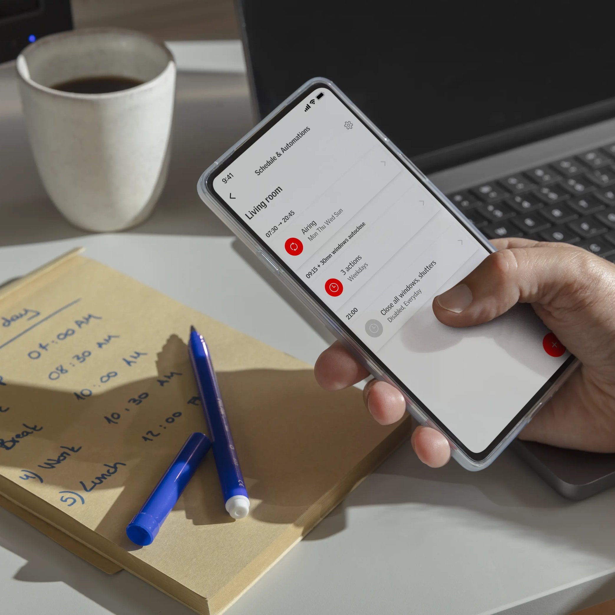 Person using smartphone scheduling app in home office with notebook and coffee.