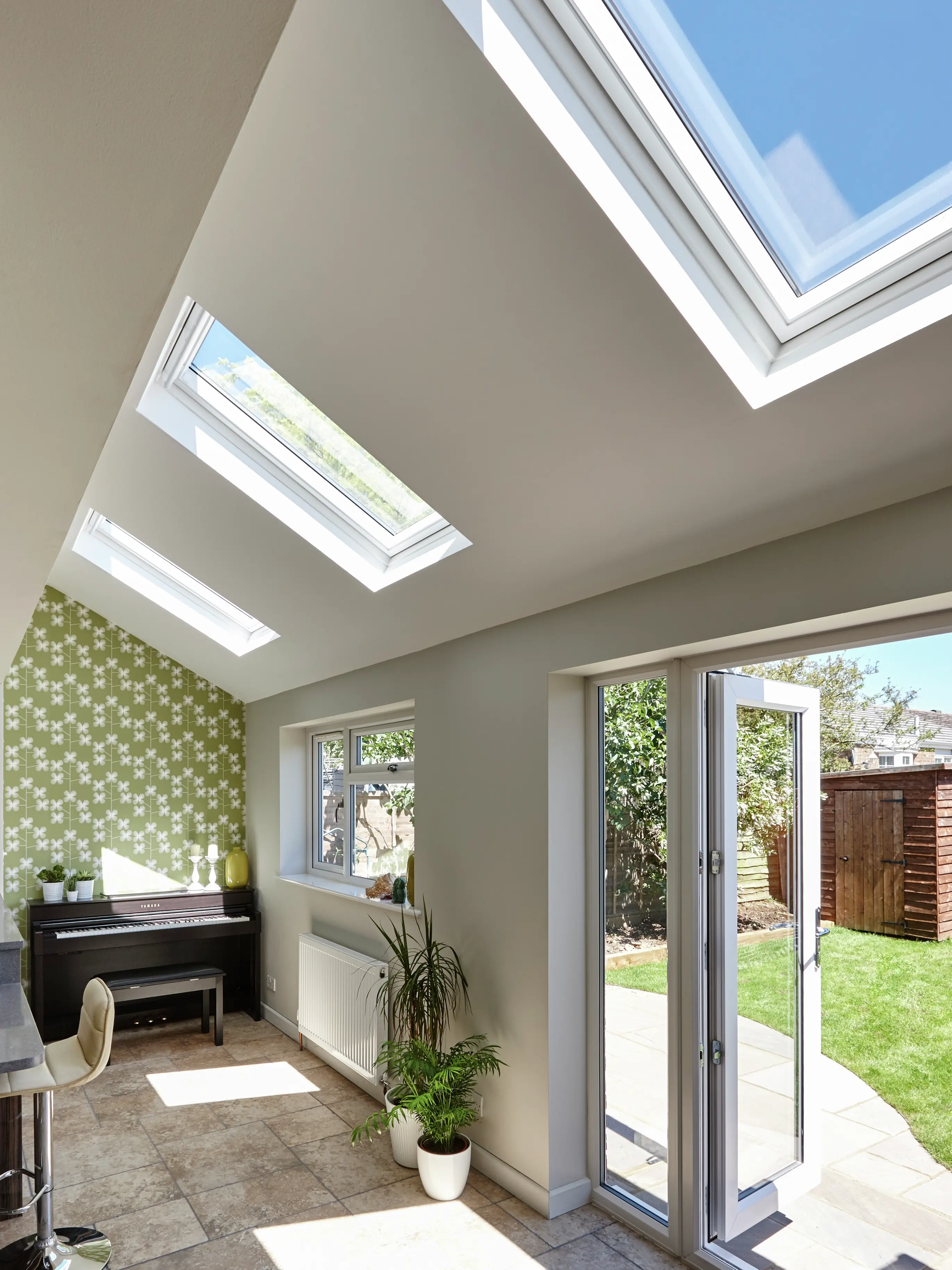 Home office with VELUX roof windows, piano, and open French doors to garden.