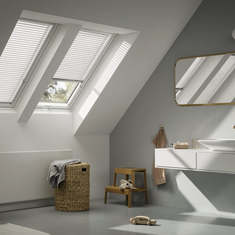 Attic bathroom with sloped ceiling and VELUX roof windows, modern design.