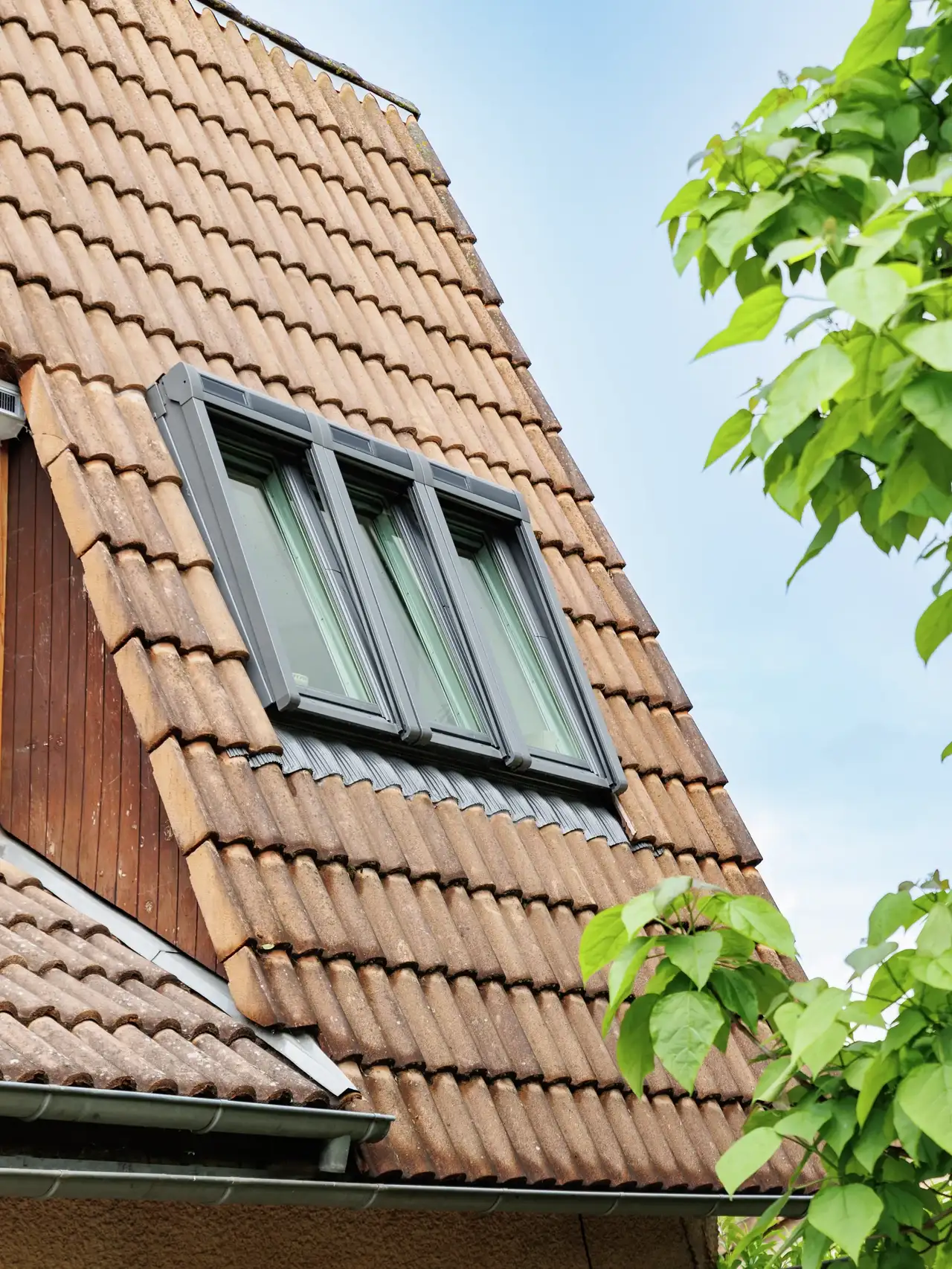 Tetto spiovente con tegole e tre finestre per tetti VELUX affiancate che portano luce e aria all’interno