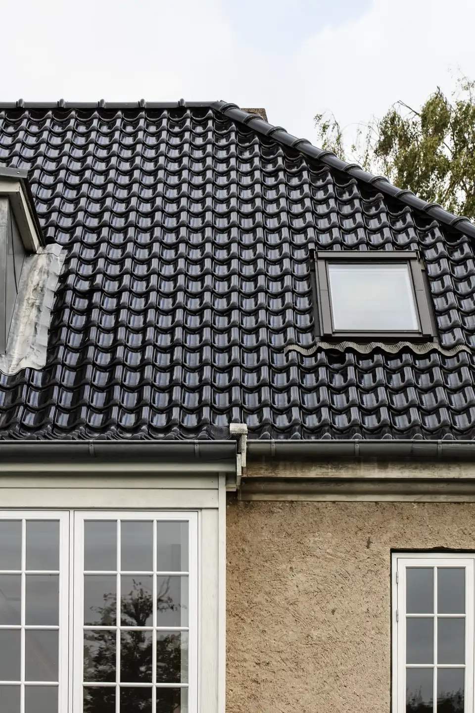 maison avec toit en tuiles sombres et une fenêtre de toit VELUX