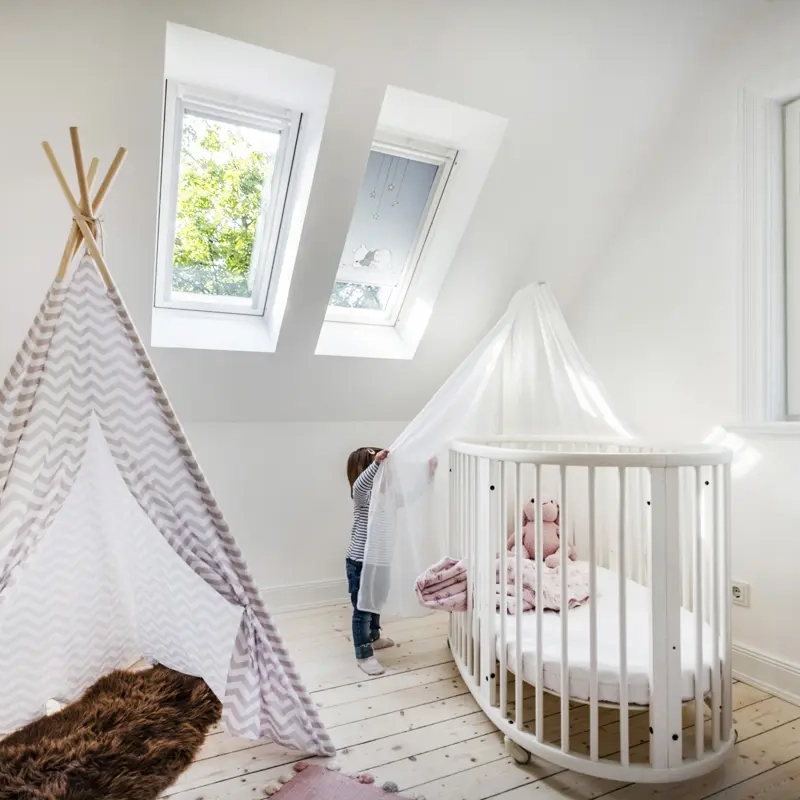 Attic nursery with sloped ceiling, VELUX roof windows, crib, and teepee tent.