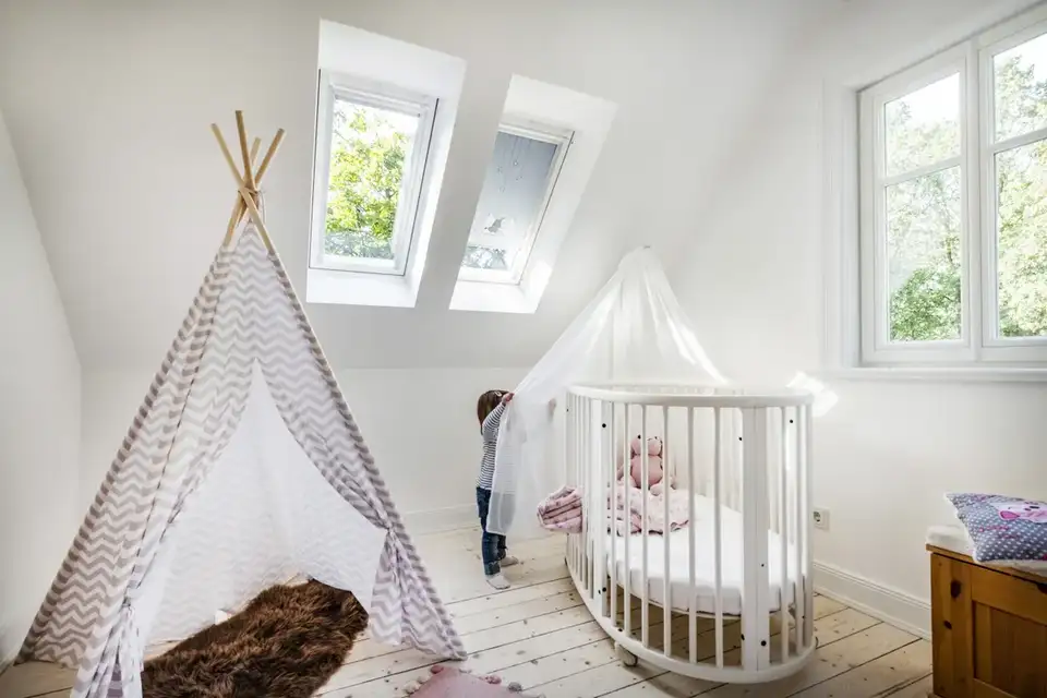 Une chambre d'enfant avec une tente de jeu de type tipi, un berceau et quelques jouets. L'environnement semble confortable et ludique, ce qui convient aux discussions sur la décoration intérieure des chambres d'enfants ou des aires de jeux.