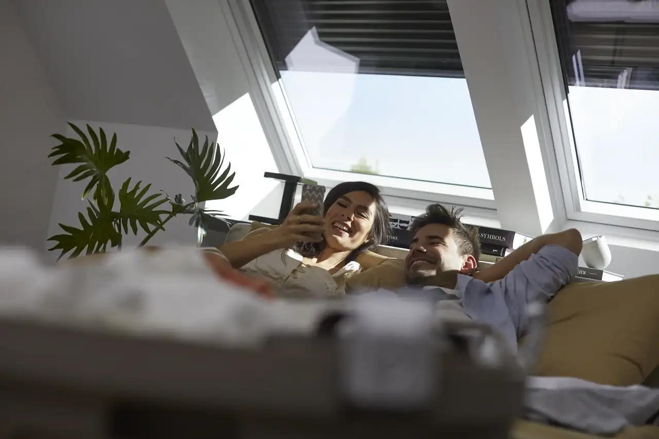 Un couple jouant avec la lumière du jour grâce aux volets roulants VELUX.