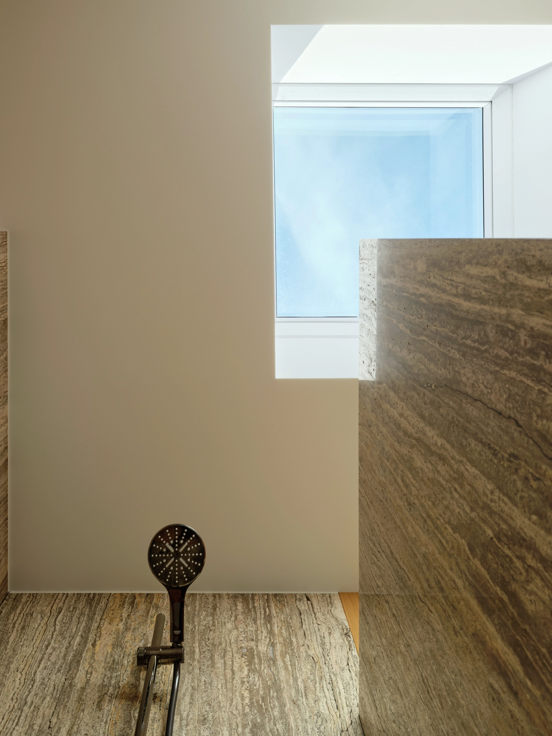 Stone-tiled walk-in shower lit from above by a VELUX flat roof window.