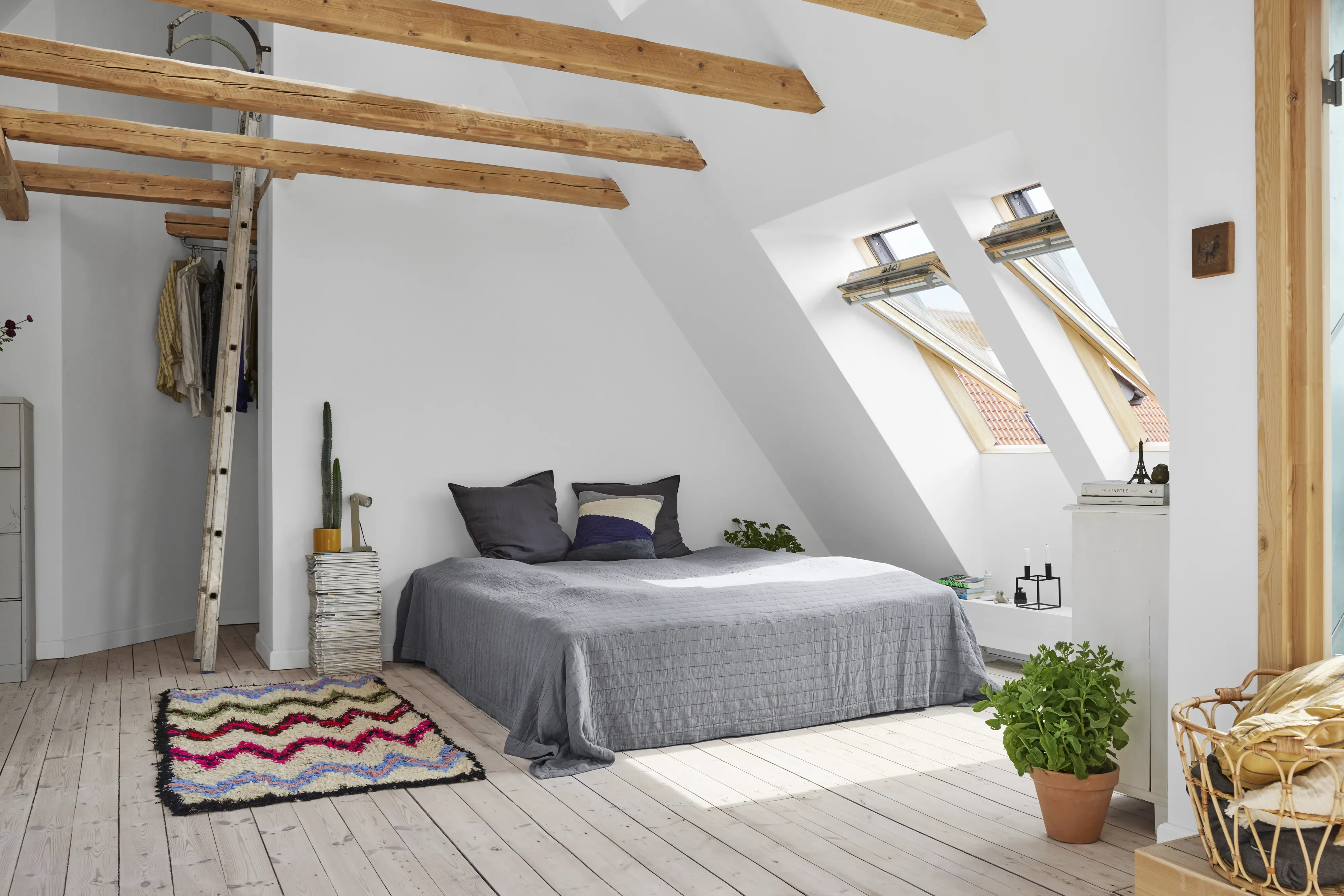 Gaiša guļamistaba zem jumta logiem ar atsegtām koka sijām. | VELUX