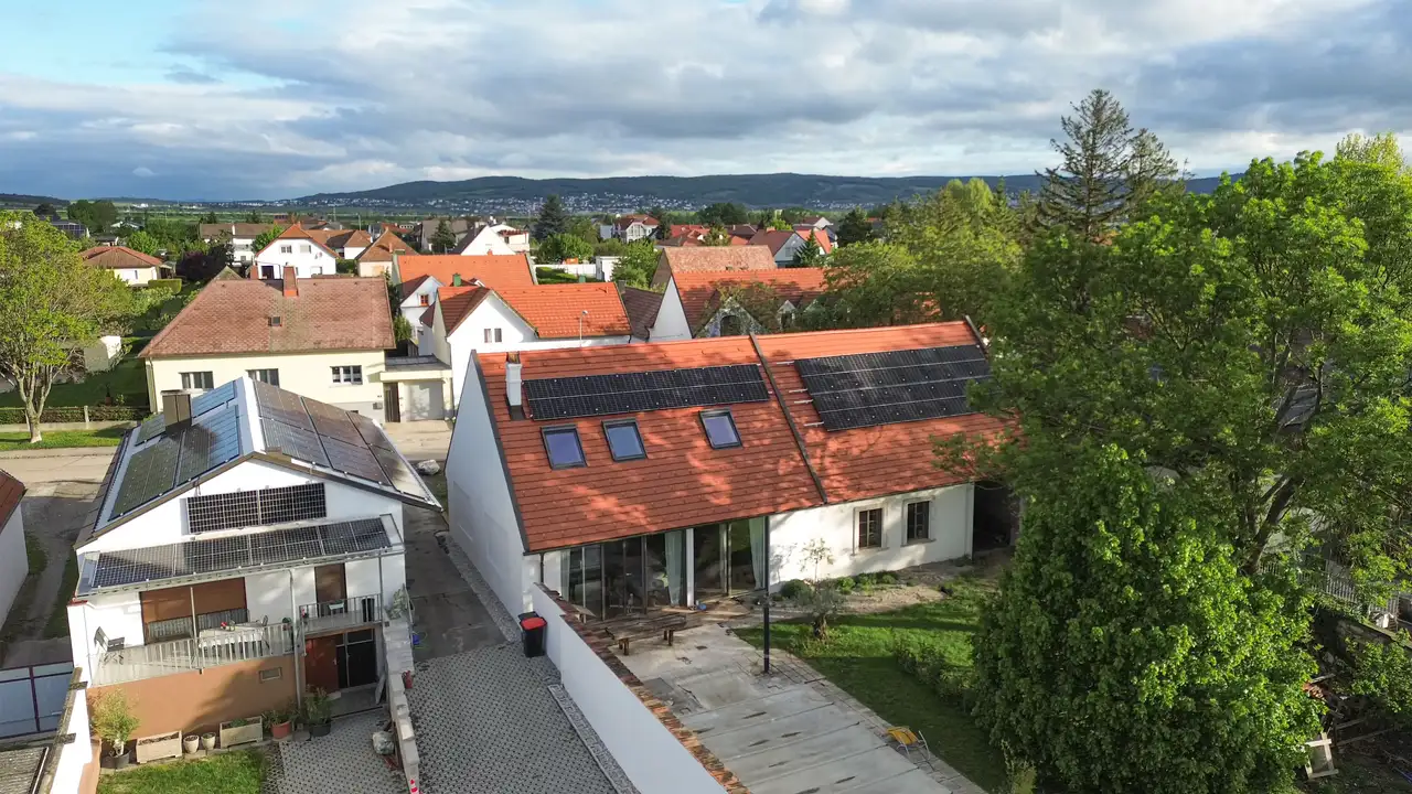 Luftaufnahme eines Hauses mit VELUX Dachfenstern und Solarpanelen, umgeben von Grünflächen und einem Wohnviertel. | VELUX Magazin