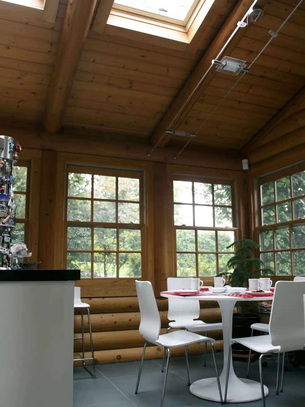 Sala da pranzo in stile rustico con travi e pareti in legno con arredi minimalisti bianchi e finestre per tetti