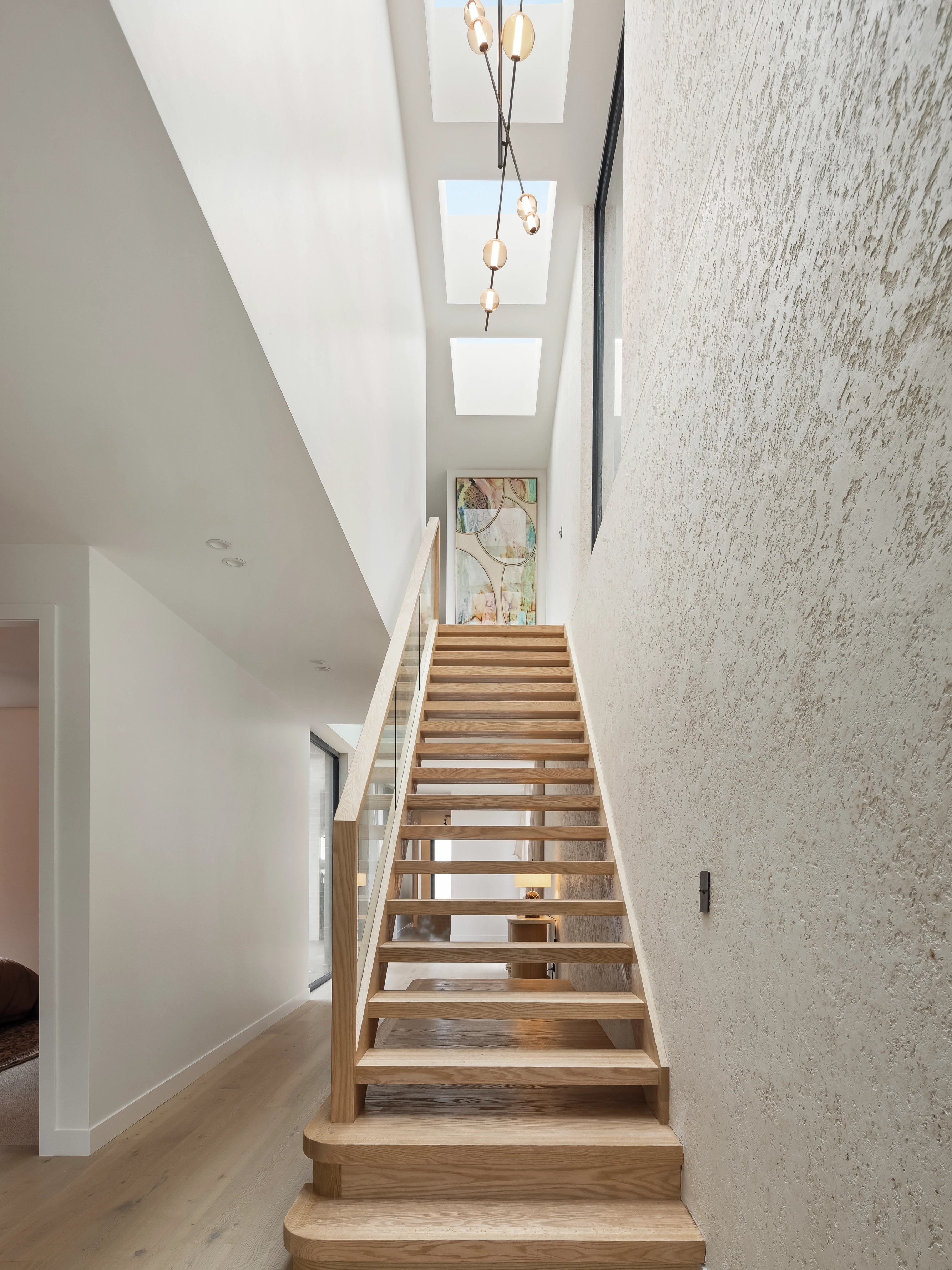 Modern wooden staircase under three VELUX flat roof windows in a bright hallway