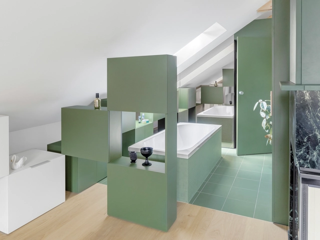 Kupaonica s zelenim zidovima i bijelim sudoperom.