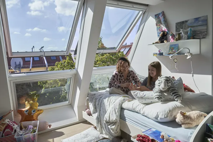 Gemütliches Kinderzimmer mit natürlichem Licht von einem VELUX Dachflächenfenster, buntem Teppich und Lernbereich.