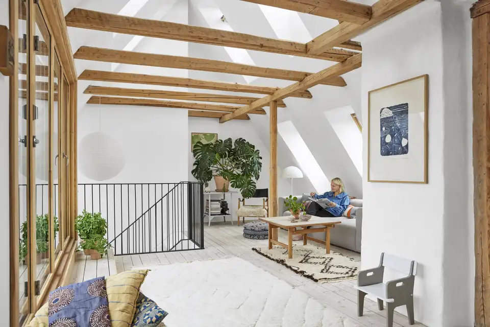 Modernizované podkrovie s odhalenými drevenými trámami a šikmými stropmi. | VELUX