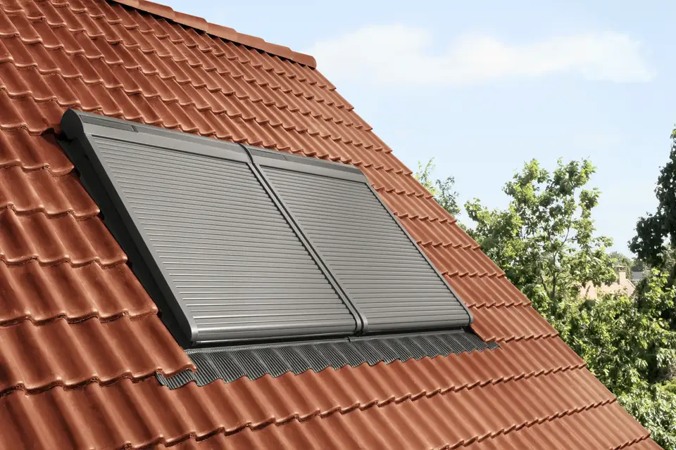 Fenêtres de toit équipées de volets roulants VELUX sur couverture en tuiles rouges
