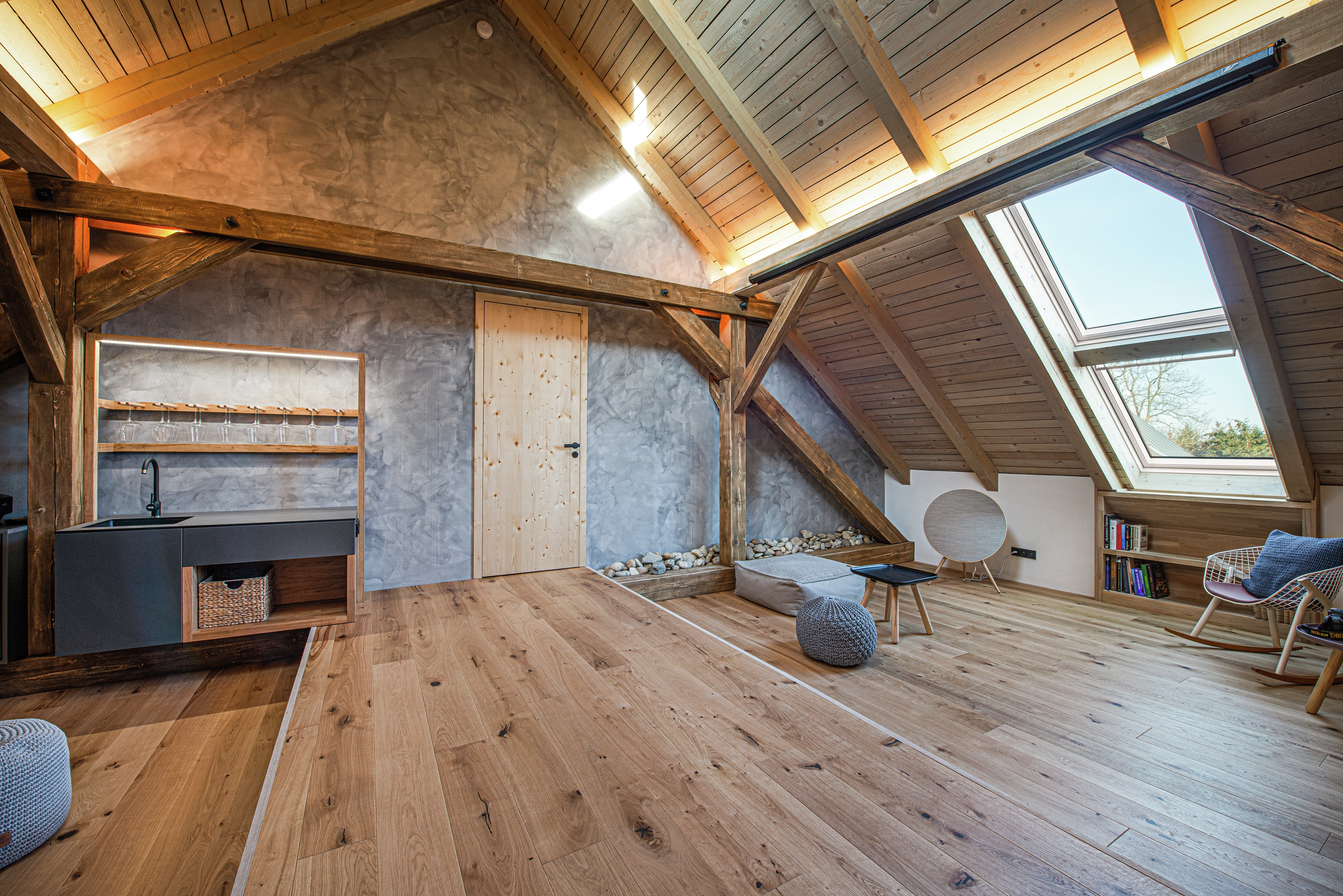 Attic room with sloped ceiling, VELUX window, and wooden rafters.