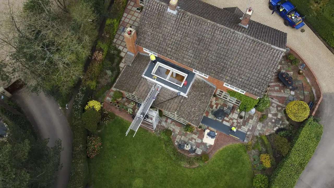 Aerial view of house with tiled roof and open VELUX roof window.