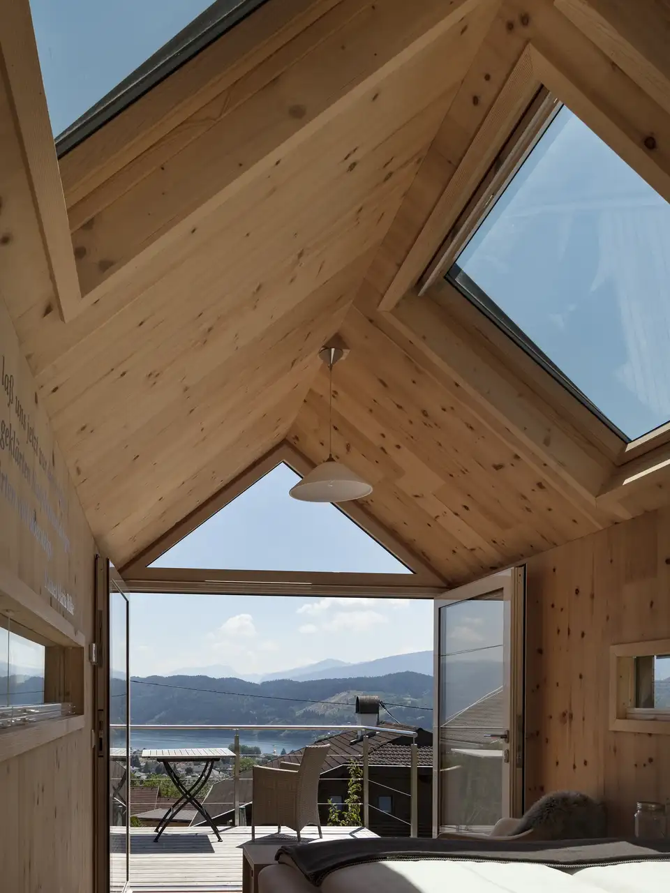 Camera in mansarda con porta finestra triangolare che affaccia su un balcone e una grande finestra per tetti 