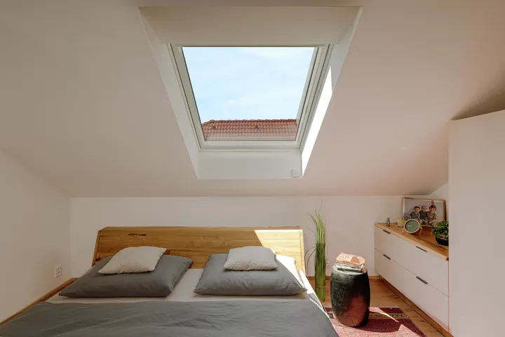 Podkrovní ložnice se střešním oknem VELUX nad manželskou postelí | VELUX