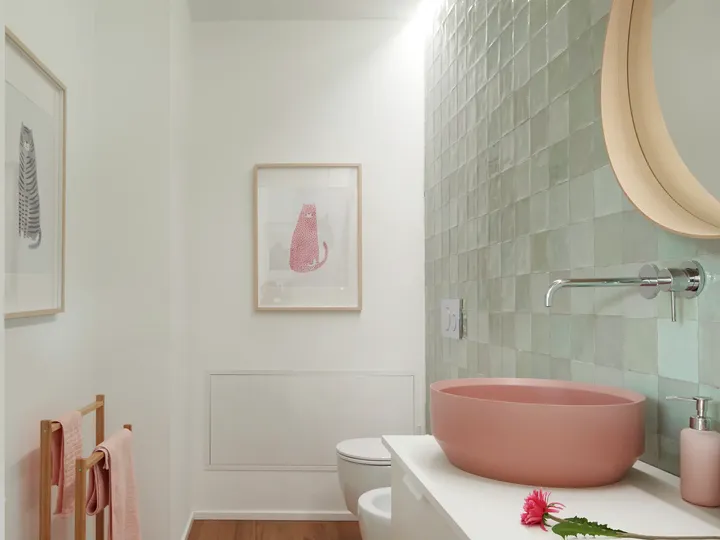 Modernes Badezimmer mit rosa Waschbecken, grün gefliester Wand und Tierkunst.