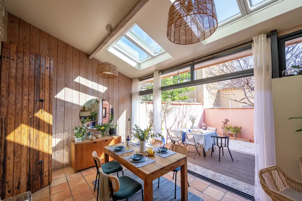 Salon avec fenêtres de toit et baie vitrée ouverte sur une terrasse