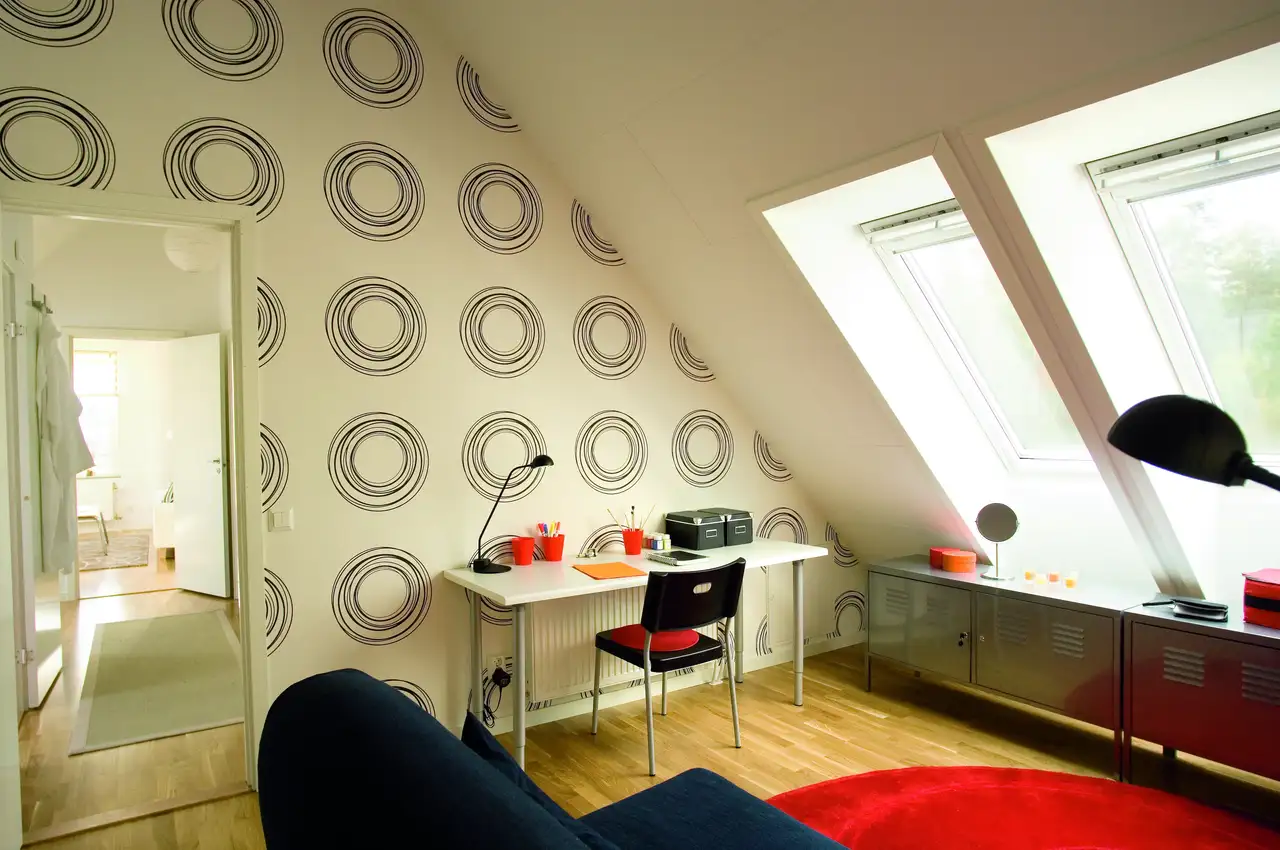 Espace de travail mansardé avec papier peint à motifs sur le mur derrière le bureau
