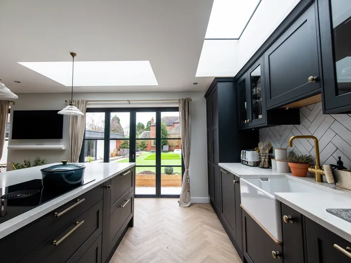 Modern kitchen with black cabinets and VELUX roof window, garden view.