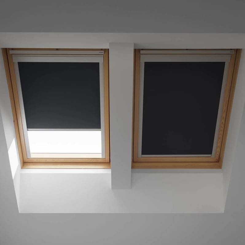 Two VELUX roof windows with dark blinds in an attic room.