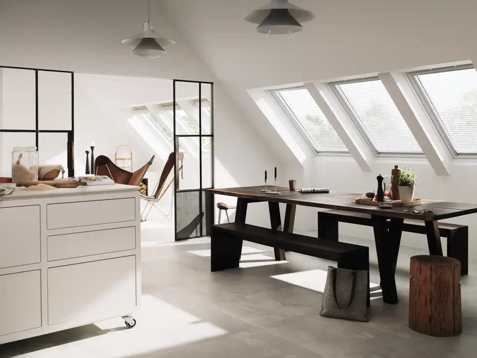 Moderne eethoek op de zolder met schuin plafond en meerdere dakvensters.