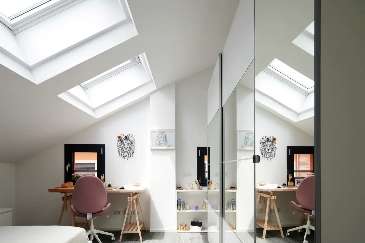 chambre d'enfants avec un bureau, une armoire à miroir et des fenêtres de toit VELUX