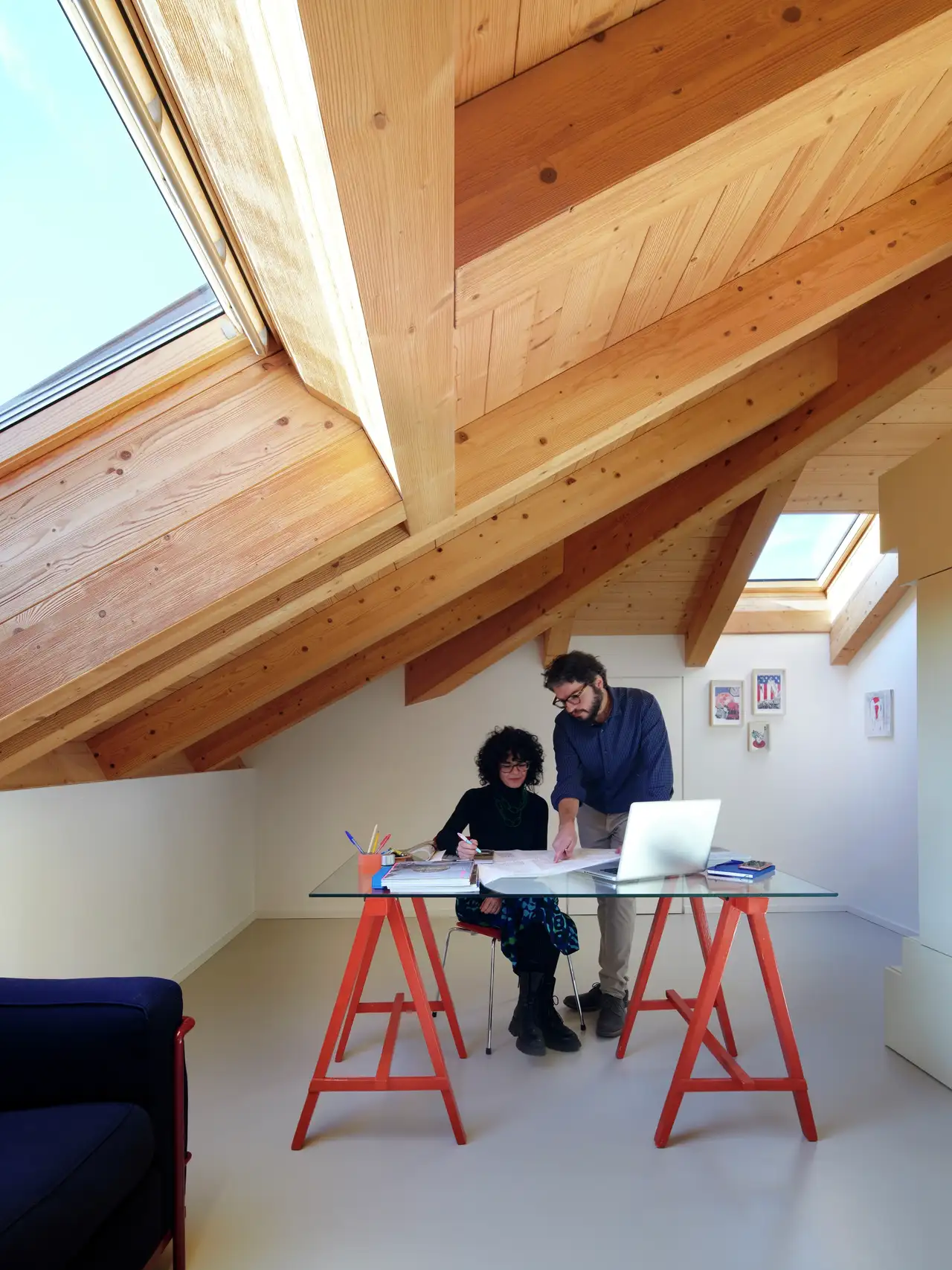 Werkruimte onder het schuine dak met VELUX vensters en glazen bureaublad. 