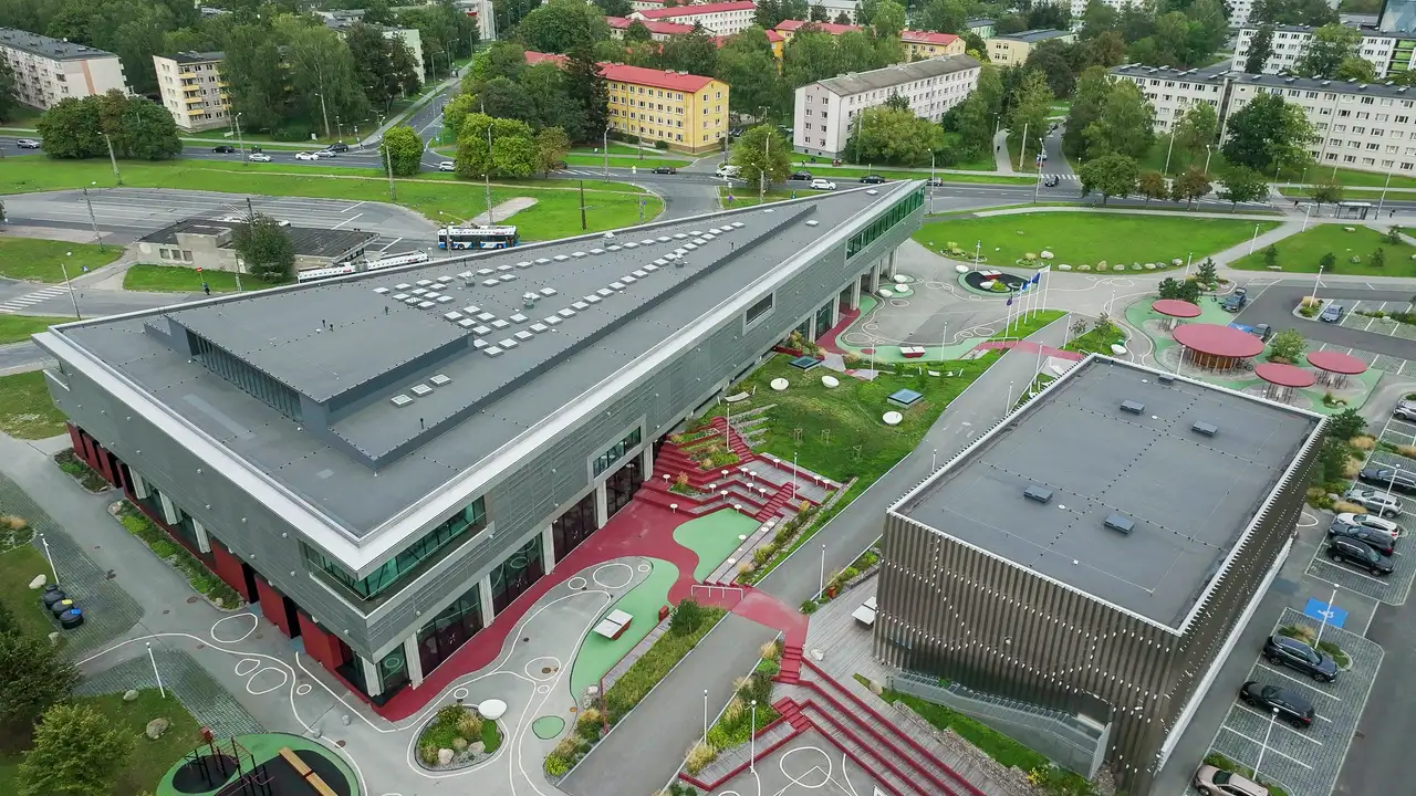 Widok z lotu ptaka na nowoczesny budynek edukacyjny z płaskim dachem i świetlikami
