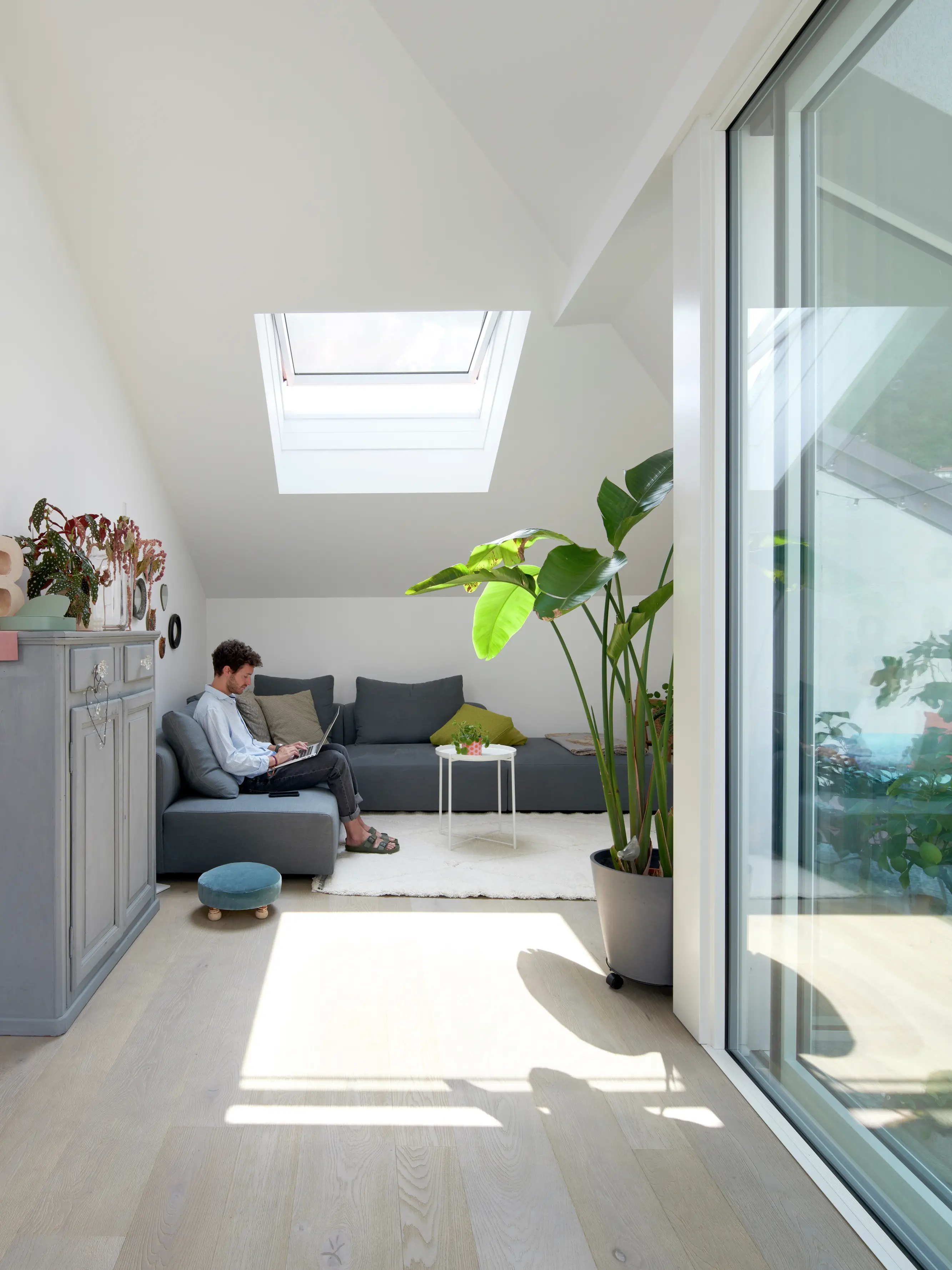 Soggiorno moderno con luce naturale proveniente da una finestra per tetti VELUX e porta scorrevole in vetro.