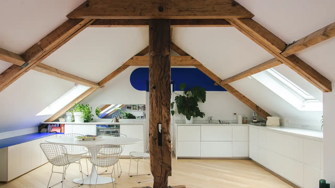  Cuisine sous combles ouverte avec fenêtres de toit VELUX, poutres en bois et mobilier blanc