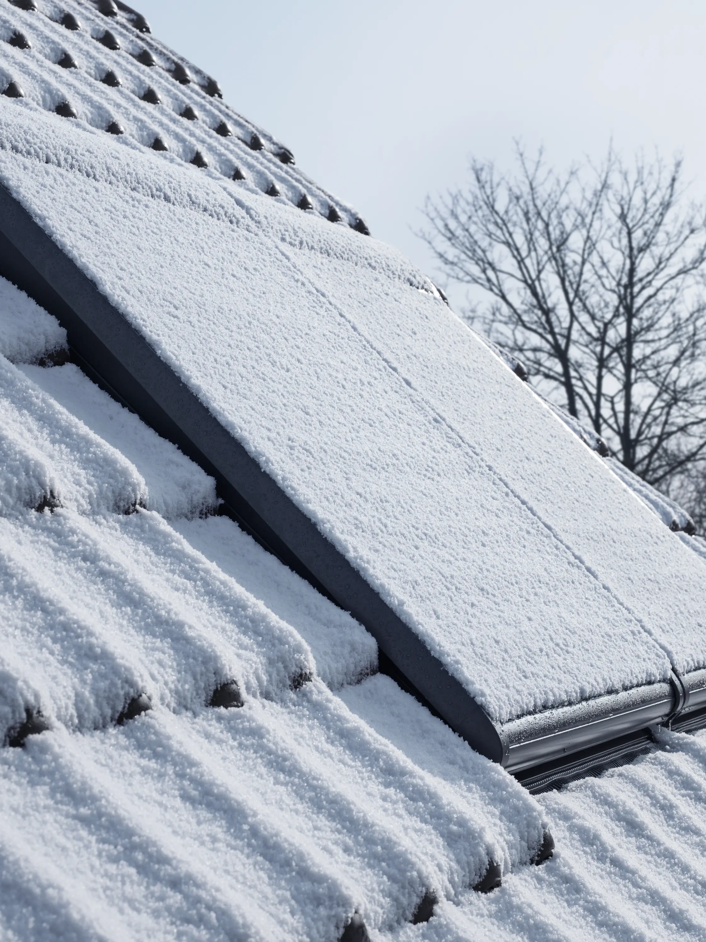 Detalle de tejado de vivienda con ventanas de tejado con persianas cubiertas de nieve