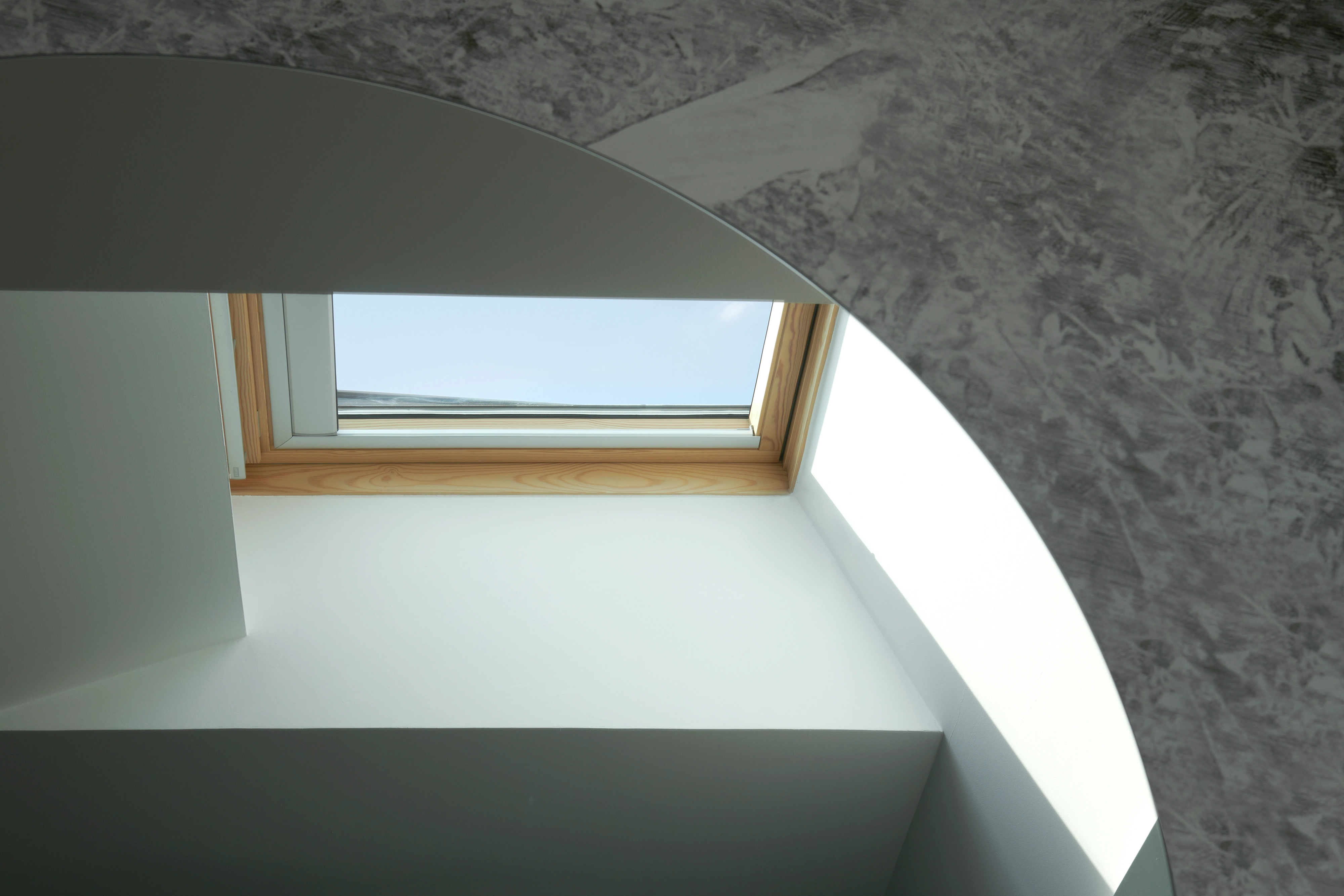 Chambre moderne avec une fenêtre de toit VELUX offrant une lumière naturelle abondante.