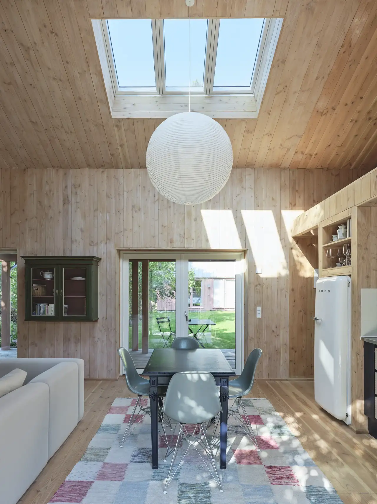 Interni in legno di una casa con soffitto spiovente, finestre per tetti VELUX e porte scorrevoli in vetro.