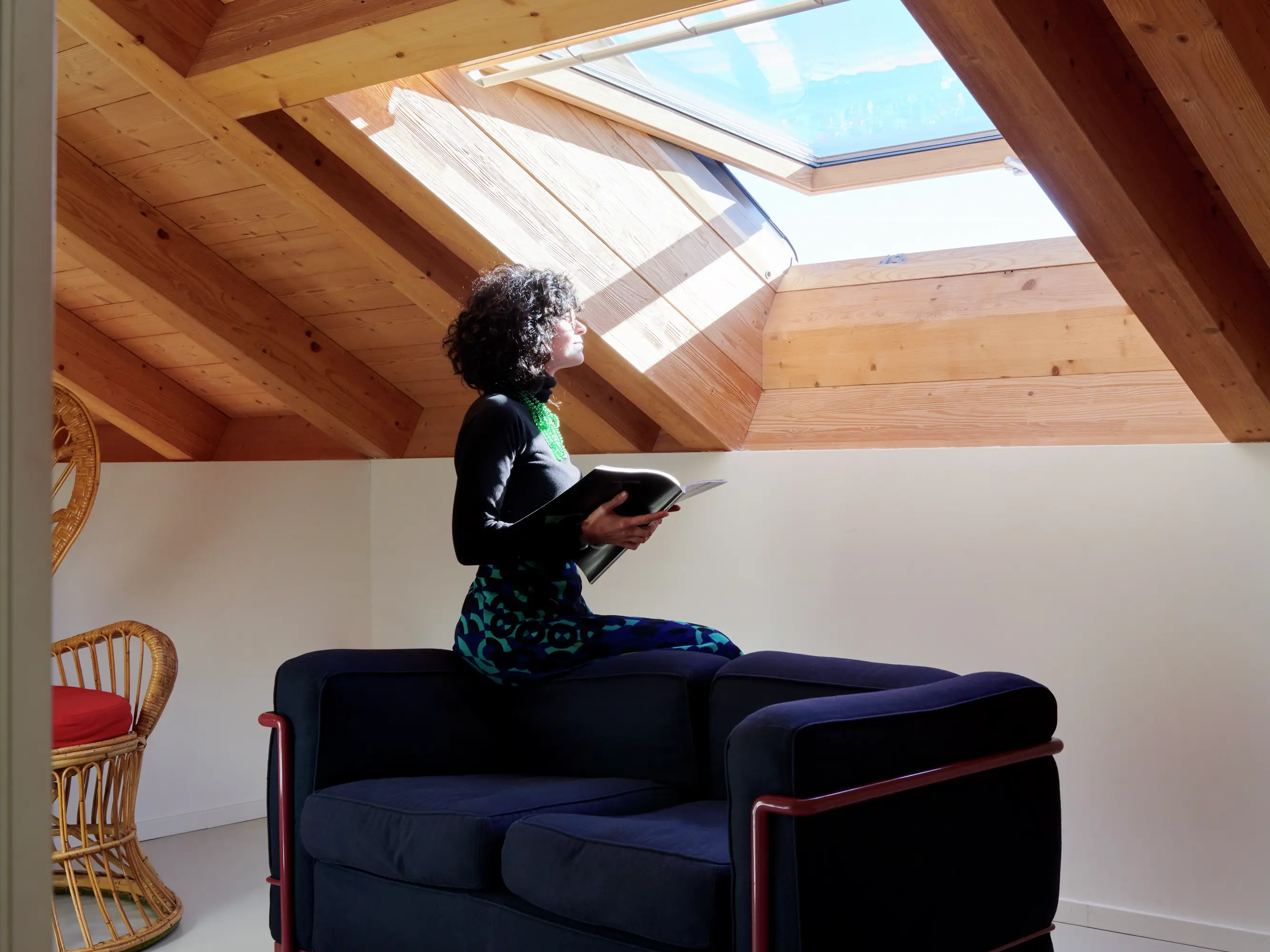 Espace de lecture confortable dans le comble avec un canapé bleu marine et des fenêtres de toit VELUX.