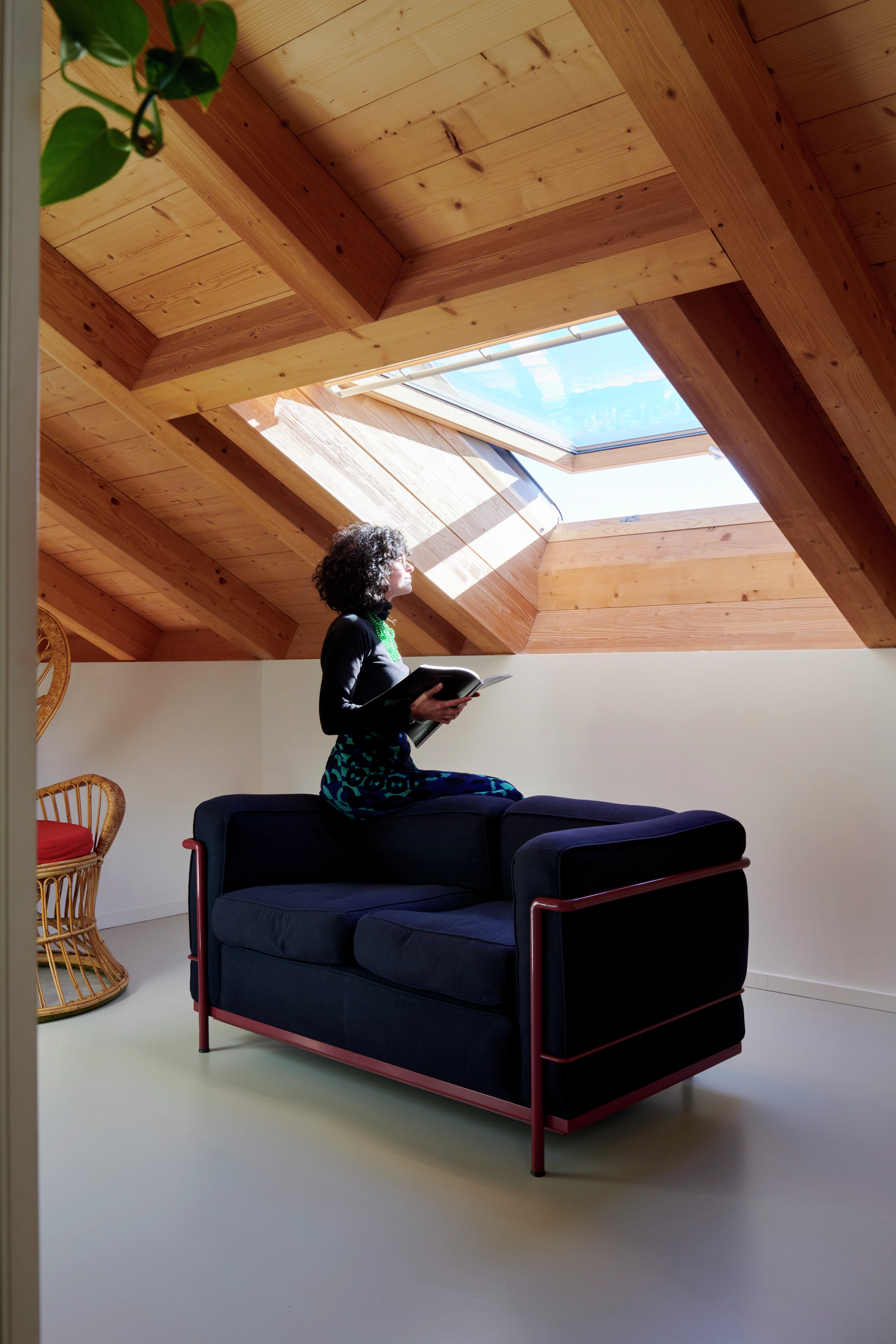 Coin lecture dans le comble avec canapé et fenêtre de toit VELUX offrant beaucoup de lumière naturelle.