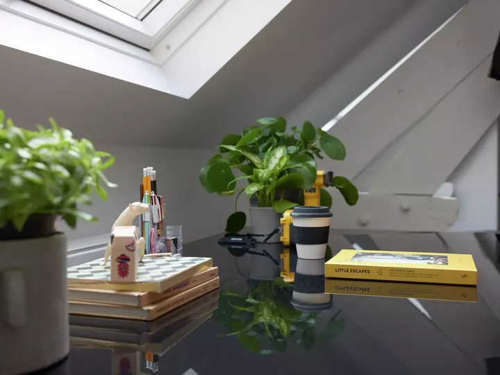 Aufgeräumter Schreibtisch mit schwarzer, glänzender Arbeitsfläche unter Dachfenster | VELUX Magazin