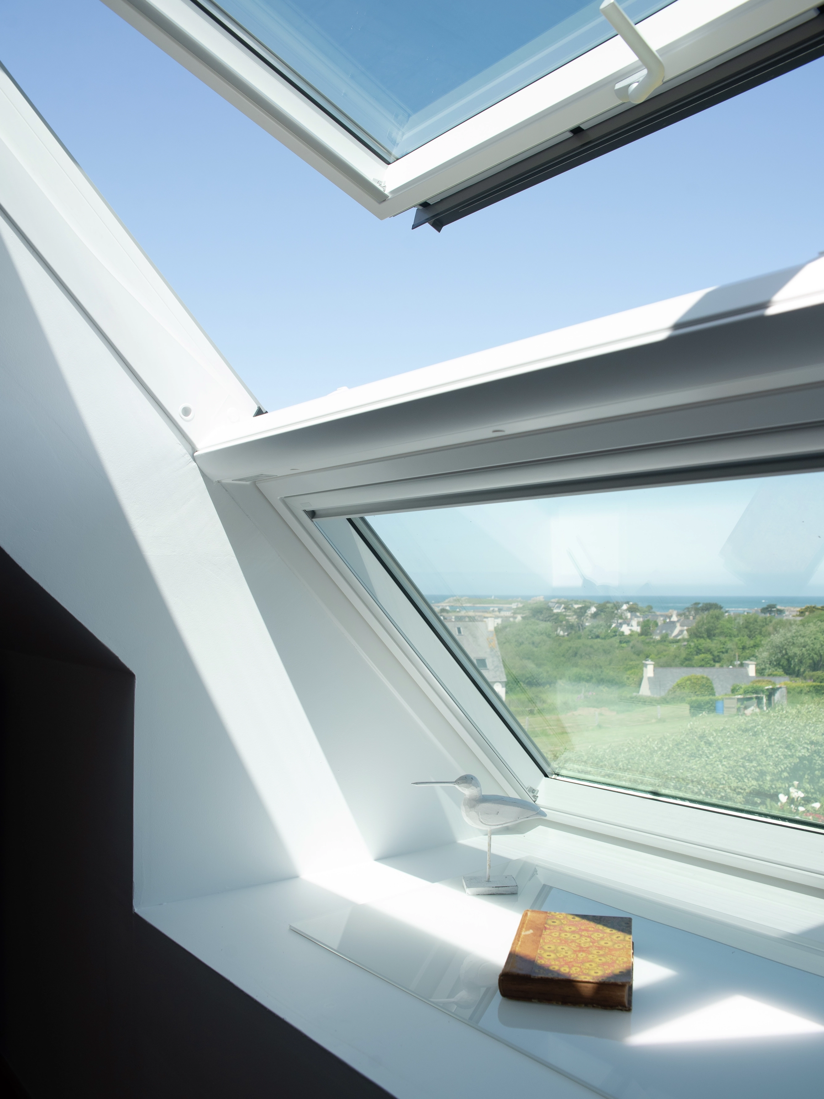 fenêtre de toit VELUX entrouverte qui laisse entrer l'air frais et la lumière