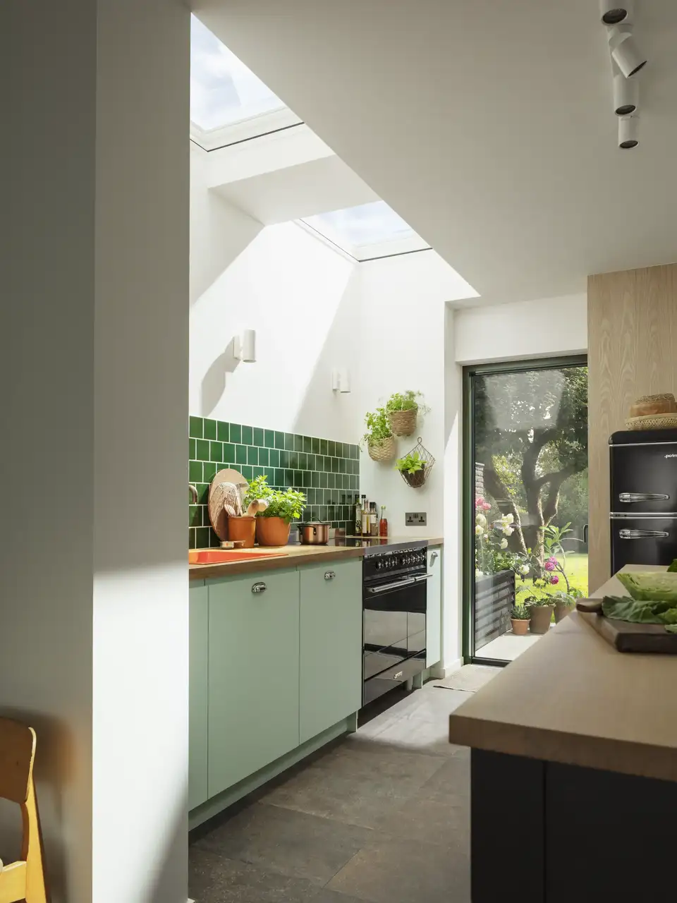 Cuisine moderne avec fenêtres de toit VELUX, mobilier vert sauge et touches naturelles 