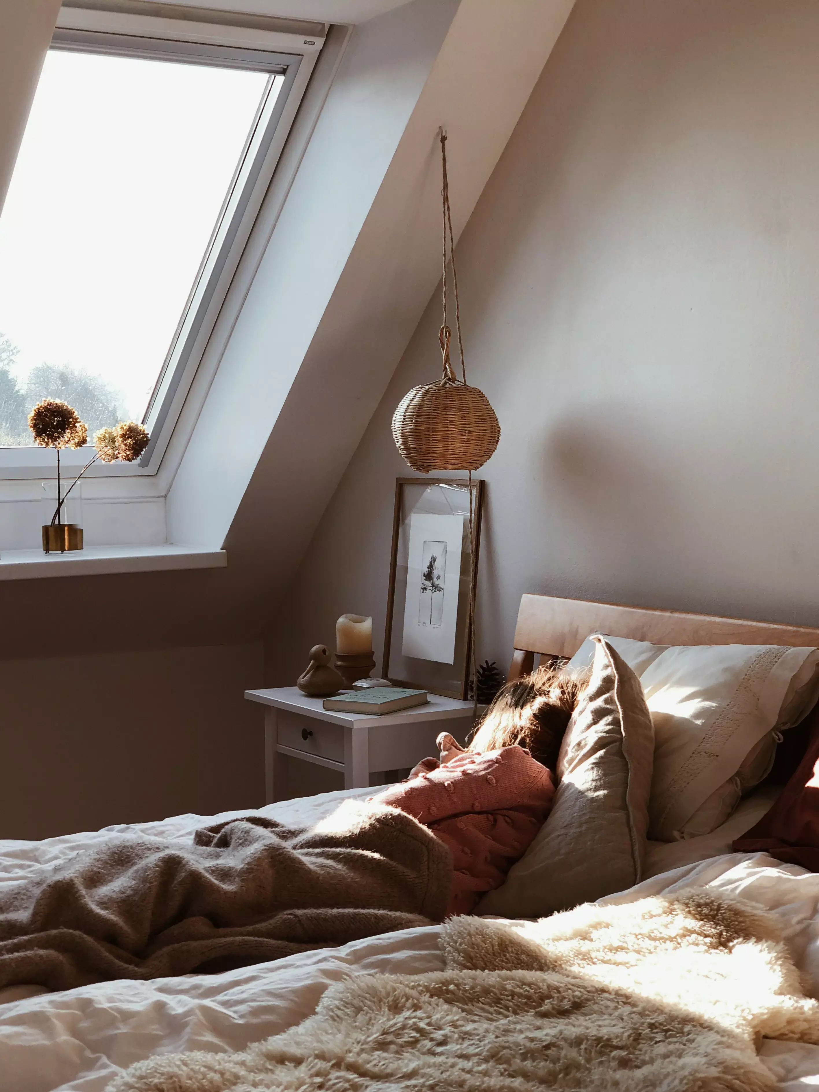 La lumière du soleil chaude à travers une fenêtre de toit VELUX illumine une scène paisible de chambre à coucher.