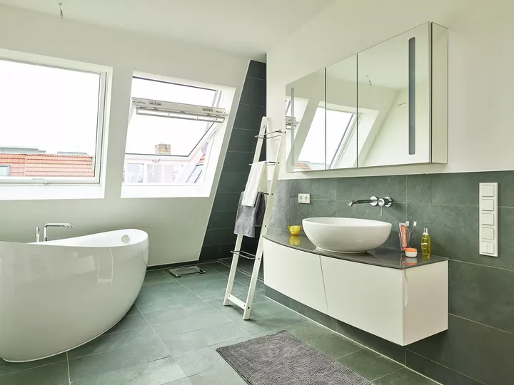 Zeitgemäßes Badezimmer mit VELUX Dachflächenfenster, freistehender Badewanne und Aufsatzwaschbecken.